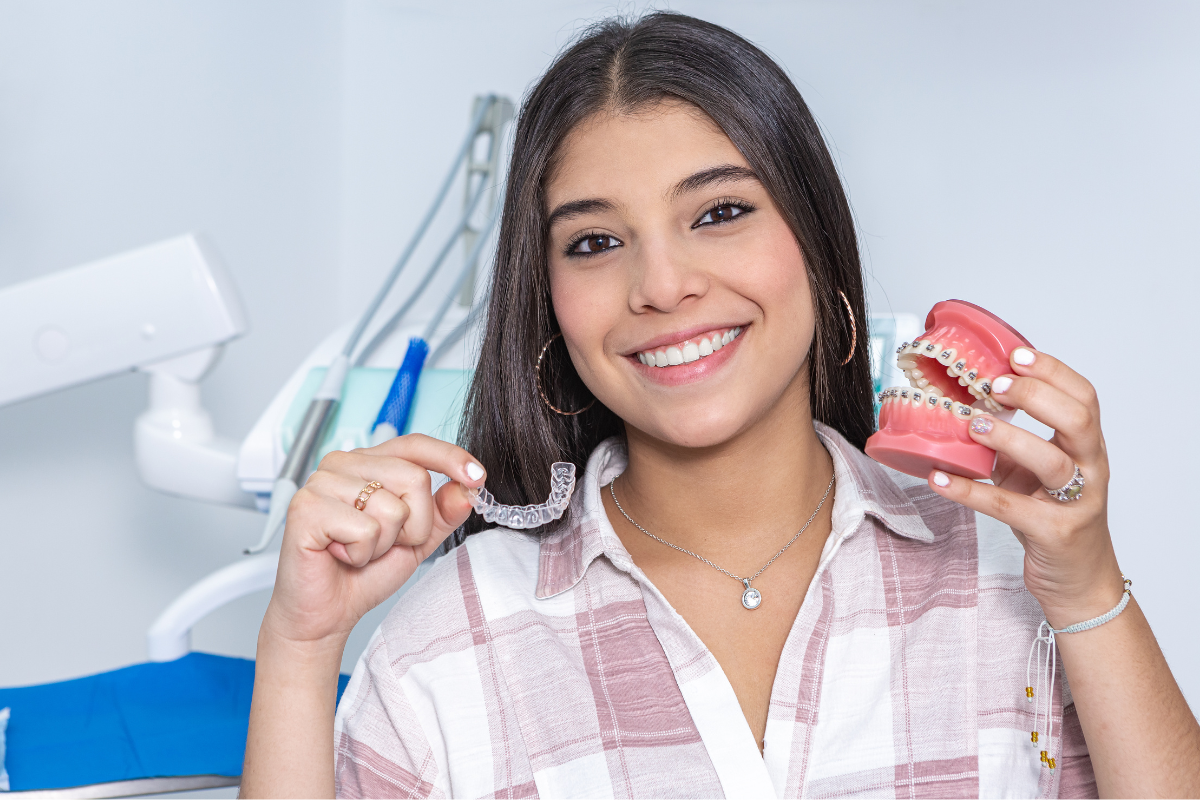 teen girl holding up braces and invisalign as her treatment options for teeth straightening