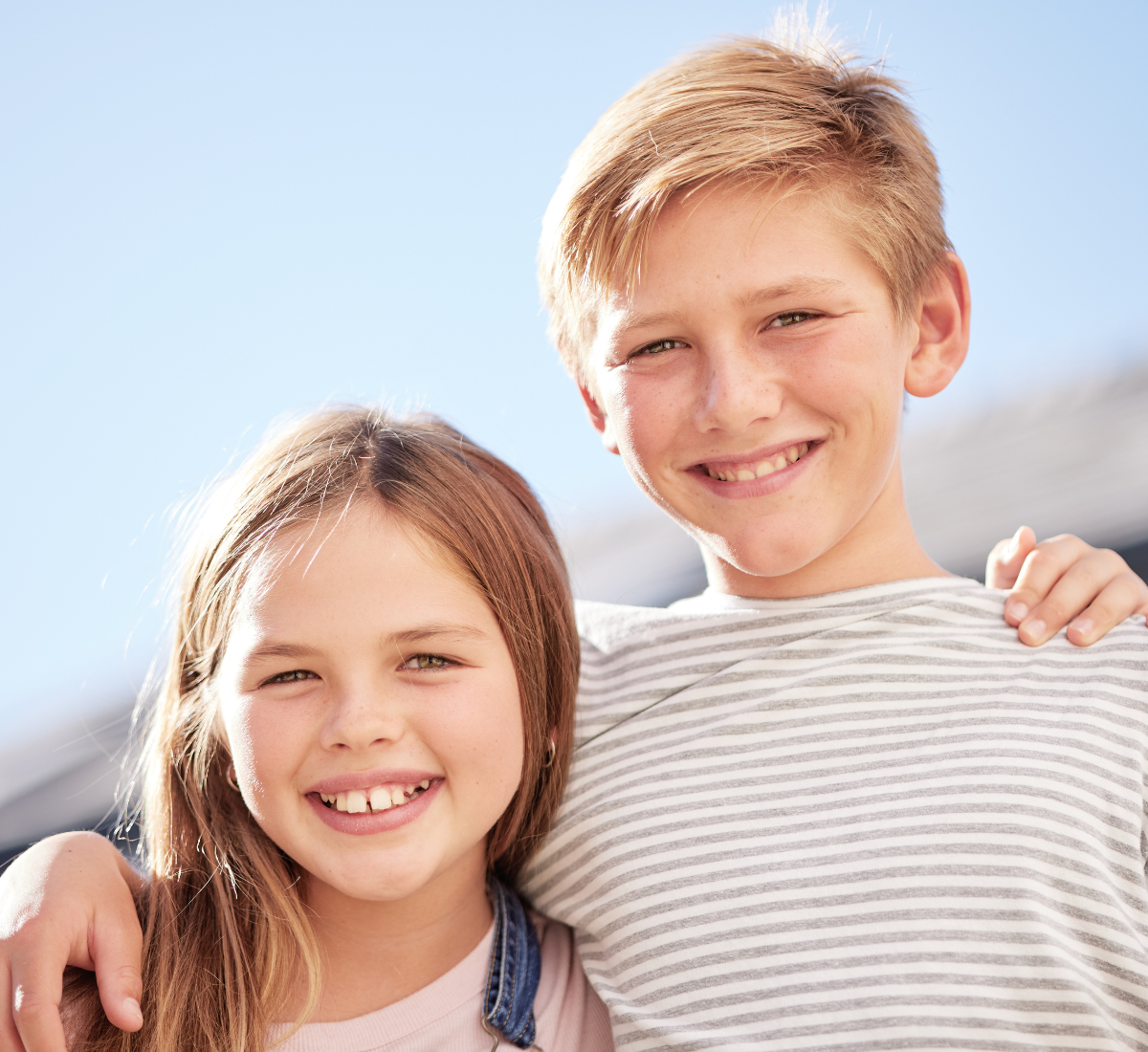 brother and sister smiling in need of early orthodontic treatment by a pediatric orthodontist