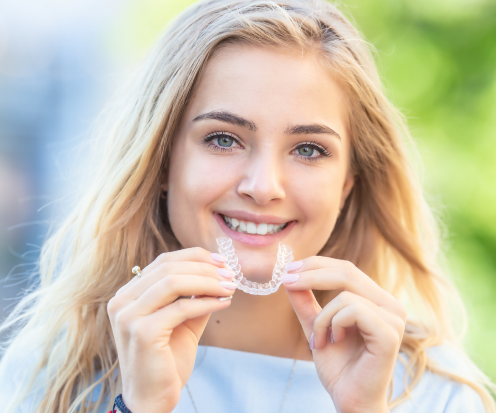 teen girl inserting invisalign clear aligner to straighten teeth