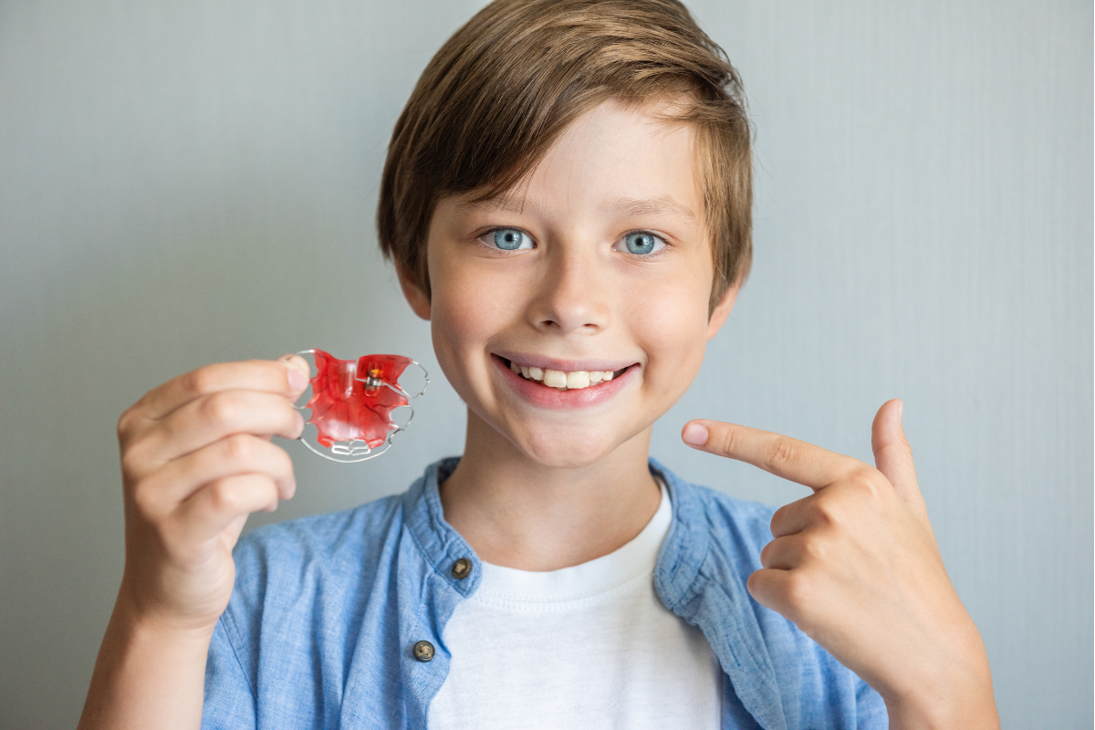 boy holding up his palate expander after proper cleaning of his orthodontic appliances