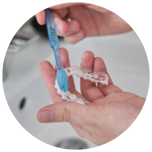 brushing clear invisalign trays with a soft bristle brush and warm water and toothpaste to keep them clean