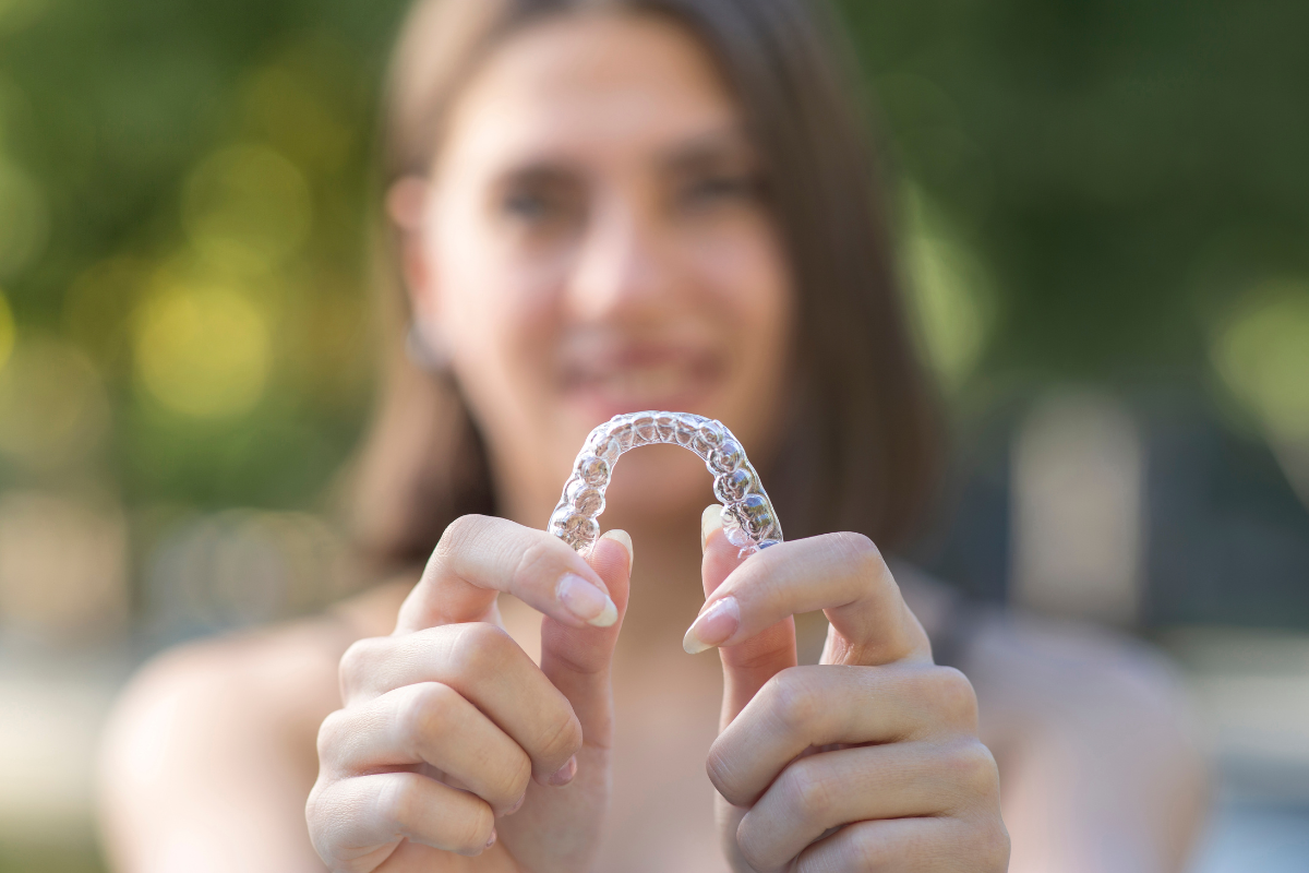 teen holding up clear invisalign teen tray used to correct teeth